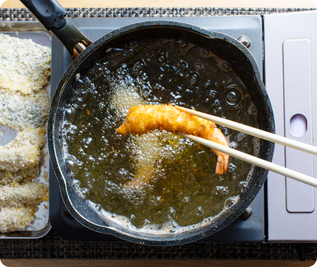 食用油をフライパンに垂らしている写真