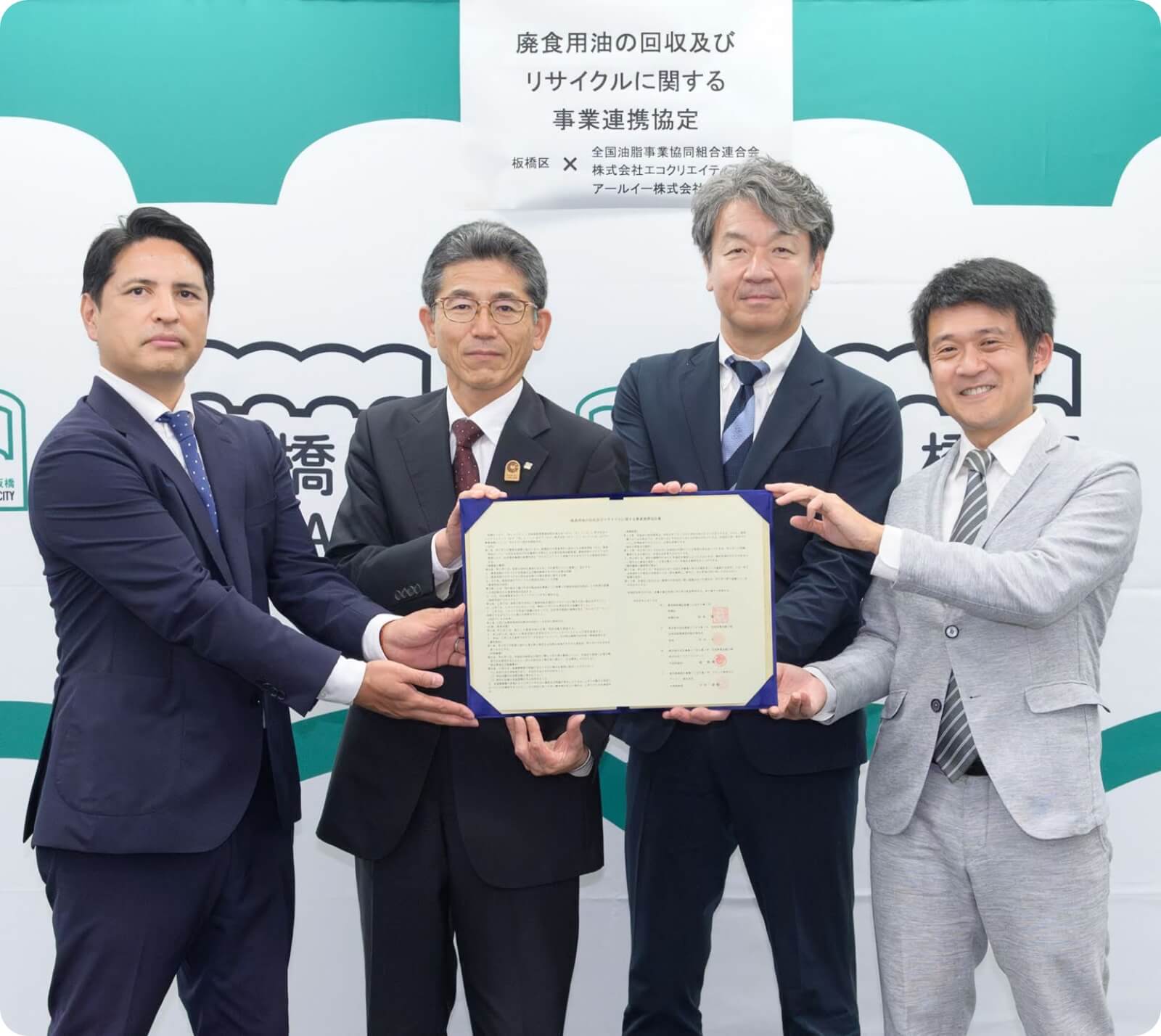 廃食用油の回収及びリサイクルに関する事業連携協定の締結式で協定書を掲げる4名